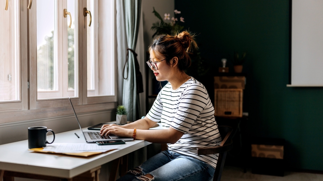 Jeune femme vêtue de façon décontractée travaillant sur un ordinateur portable au