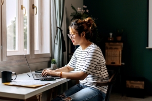 Jeune femme vêtue de façon décontractée travaillant sur un ordinateur portable au