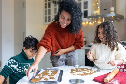 Image d’une femme préparant des biscuits avec deux enfants.